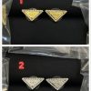 Gold and silver triangle fashion earrings on black background.