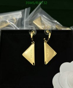 Gold designer triangle earrings on black display.