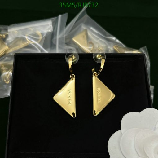 Gold designer triangle earrings on black display.