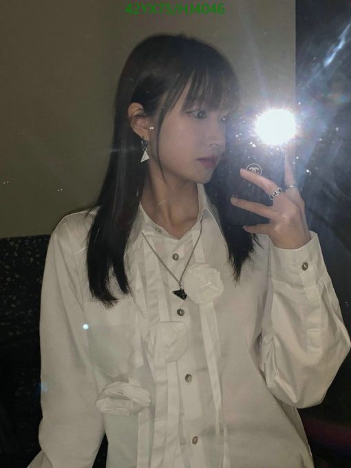 Woman taking mirror selfie with flash, wearing white shirt.