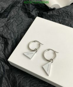 Silver designer triangular hoop earrings on white box.