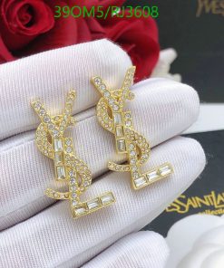 Gold designer logo earrings with crystals on white glove.