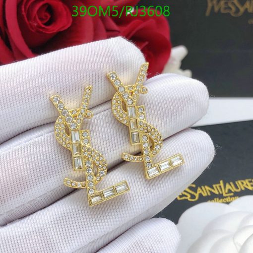 Gold designer logo earrings with crystals on white glove.