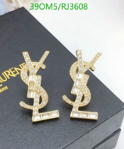 Gold crystal dollar sign earrings on black box.