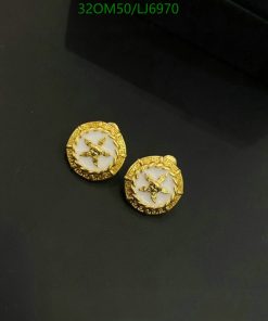 Gold bee motif earrings on dark surface.