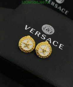 Versace gold Medusa head earrings on black box.