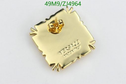 Gold square pin with embossed lettering.