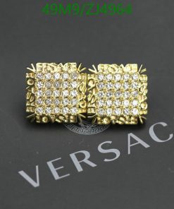 Gold Versace cufflinks with crystals on dark background.