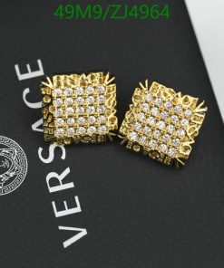 Gold Versace cufflinks on branded black backdrop.