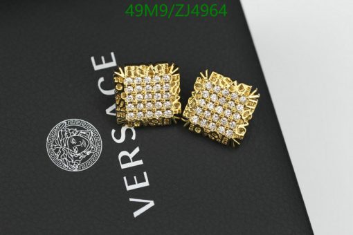 Gold Versace cufflinks on branded black backdrop.