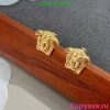 Gold lion head stud earrings on wooden surface.