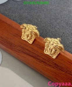 Gold lion head stud earrings on wooden surface.