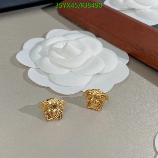 Gold lion head earrings on white surface.