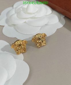 Gold lion head earrings on white floral background.