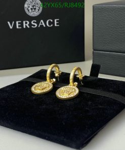 Versace gold medusa head earrings on display.