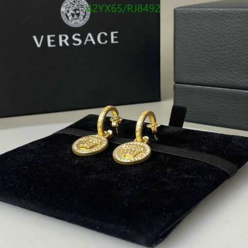 Versace gold medusa head earrings on display.