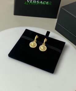 Gold coin pendant earrings on black velvet stand.