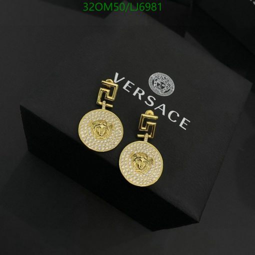 Gold designer earrings on black box with logo.