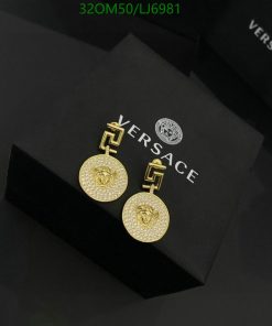 Versace gold medallion earrings on black background.