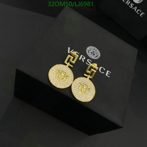 Gold Versace medallion earrings on black box.