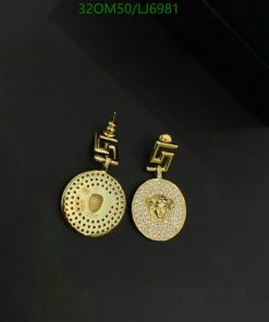 Gold dangle earrings with intricate design on black.