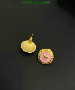 Gold earrings with pink accents on black background.