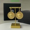 Gold coin-shaped earrings on display stand.