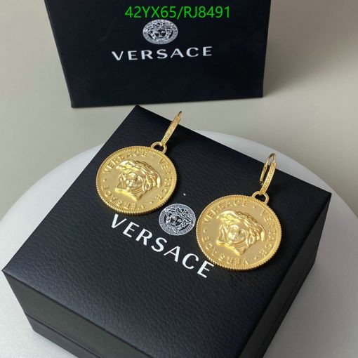 Versace branded gold medallion earrings on black box.