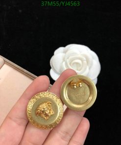 Hand holding golden lion-designed buttons with white flower background.