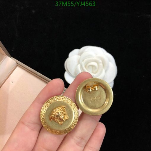 Hand holding golden lion-designed buttons with white flower background.