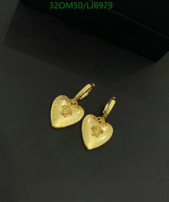 Gold heart-shaped pendant earrings on dark surface.