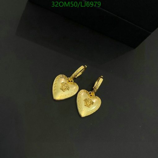 Gold heart-shaped pendant earrings on dark surface.