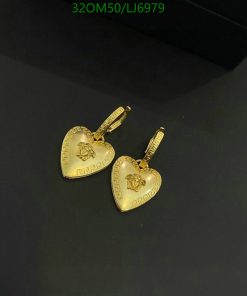 Gold heart-shaped earrings on dark background.