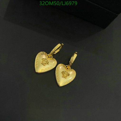 Gold heart-shaped earrings on dark background.