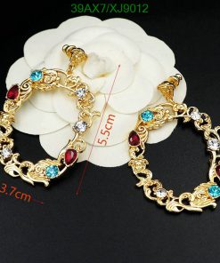 Gold-tone earrings with multicolor gemstones on white flower.