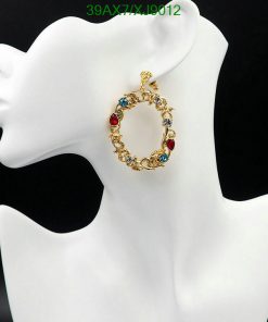 Gold earring with multicolored stones on mannequin.