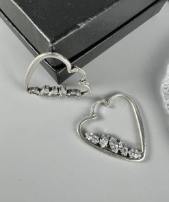 Silver heart-shaped earrings with diamonds on display.