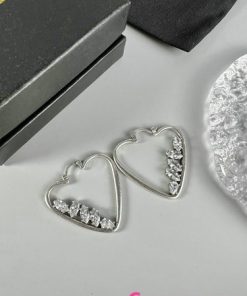 Silver heart-shaped earrings with diamonds on gray background.