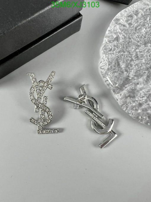 Designer logo pendant and earrings set on table.