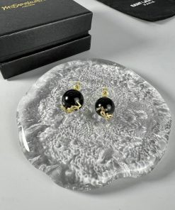 Black and gold earrings on textured surface with boxes.