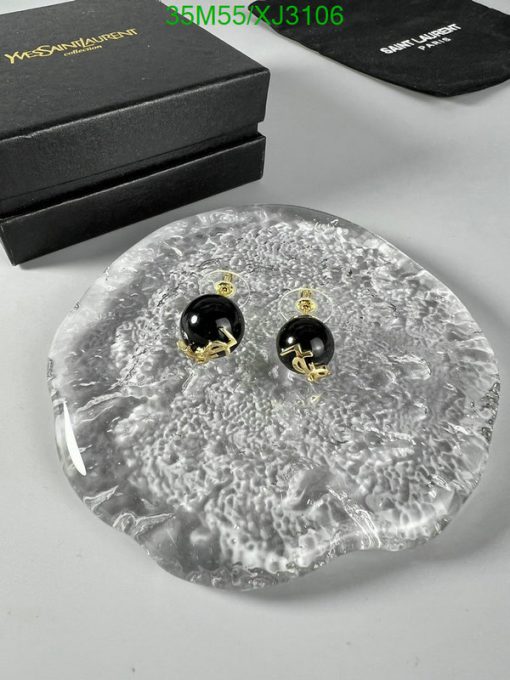 Black and gold earrings on textured surface with boxes.