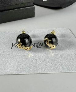 Black and gold designer earrings on display.