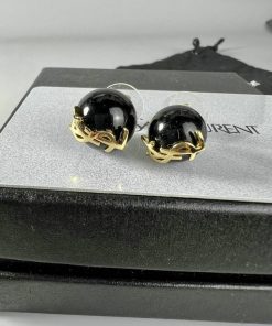 Black and gold earrings on display stand.