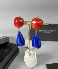 Red and blue drop earrings on display stand.