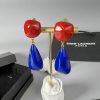 Red and blue designer earrings on display stand.