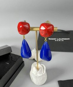 Red and blue designer earrings on display stand.