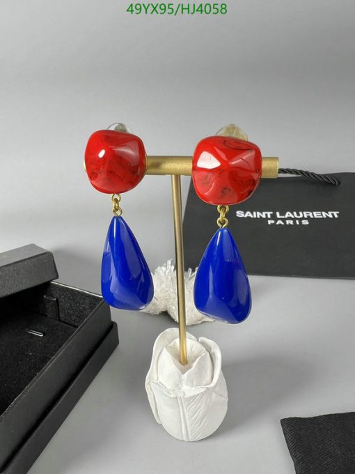 Red and blue designer earrings on display stand.