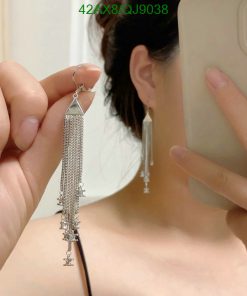 Person holding tassel earrings, reflected in mirror.