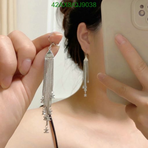 Person holding tassel earrings, reflected in mirror.