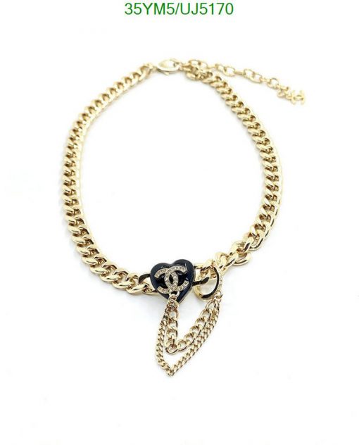 Gold chain bracelet with black charm and pendant.